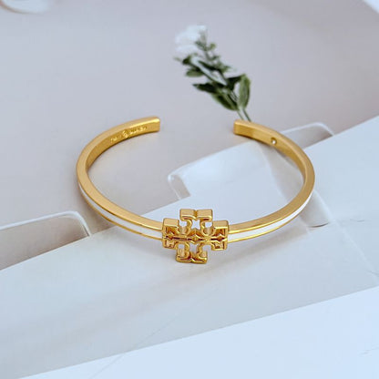 Open gold-tone metal bangle with cutout logo charm, hinged style