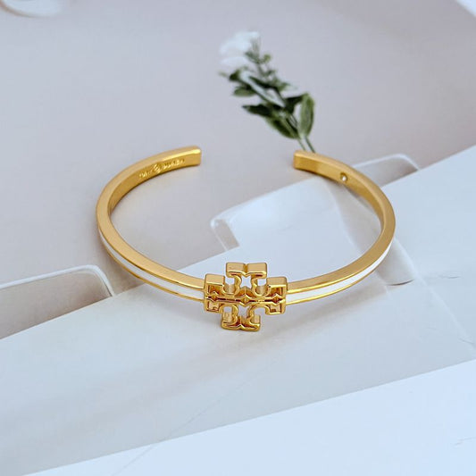 Open gold-tone metal bangle with cutout logo charm, hinged style