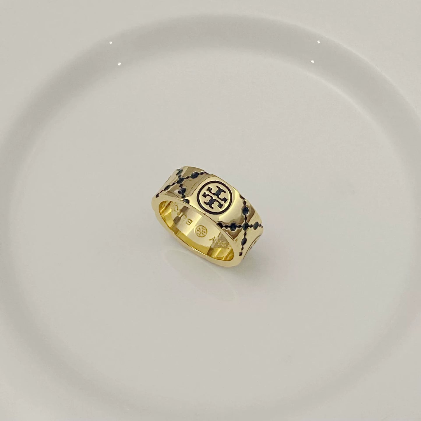 Round logo metal ring with white enamel clover pattern on gold-tone band