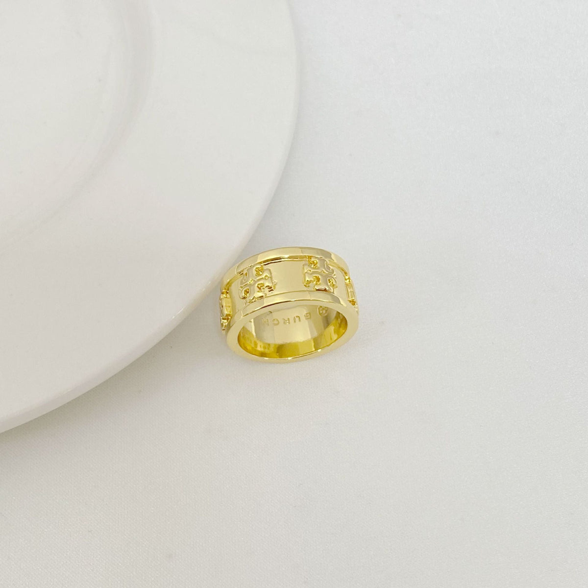 Gold letter band ring with patterned engraving on top and open side profile