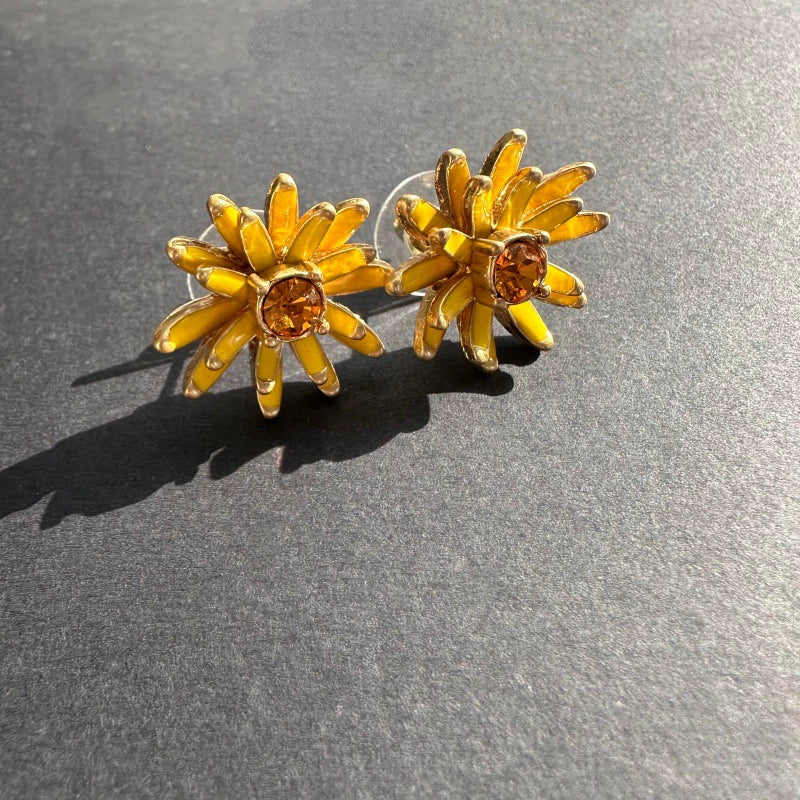 Gold enamel flower stud earrings with yellow petal accents and amber center stones