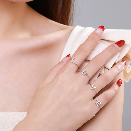 Adjustable silver-tone bracelet worn on hand with dangling pavé letter charm detail