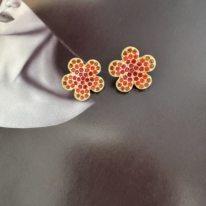 Gold-tone floral stud earrings with red and clear rhinestones
