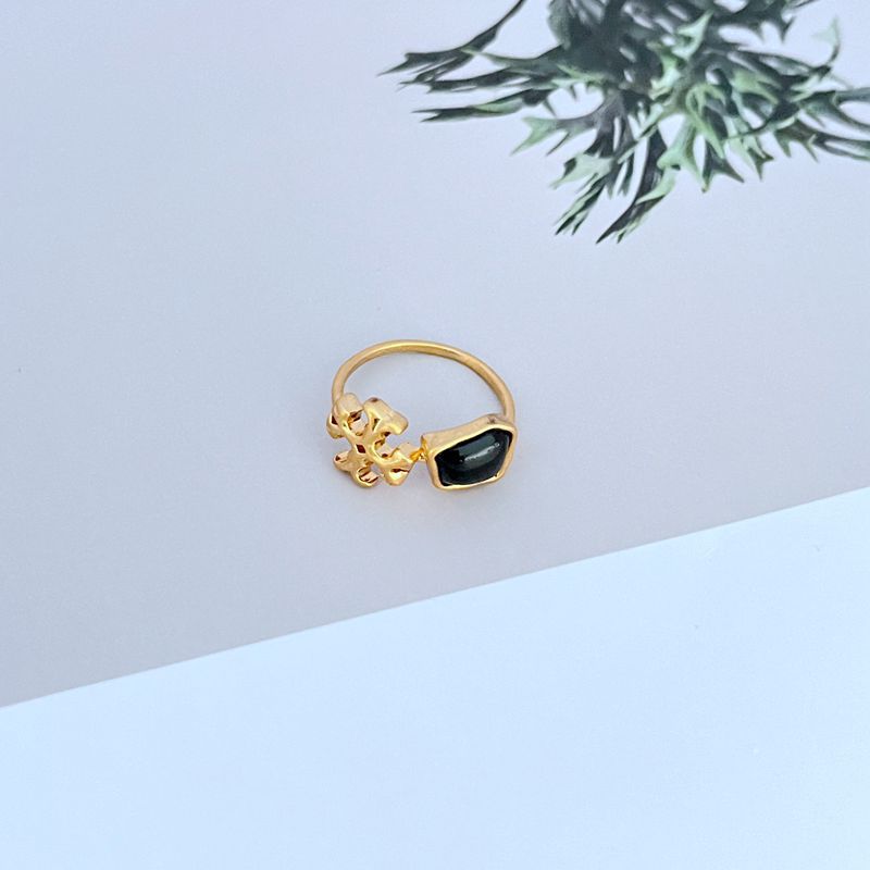 Gold-tone matte logo ring with black acrylic stone and ornate logo setting