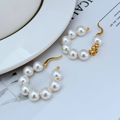Two gold-tone hoop earring sets with round white pearl beads and decorative charm