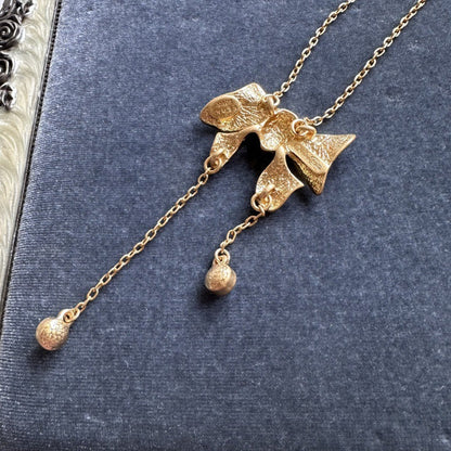 Gold-tone bow pendant necklace with round crystal drops and chain tassels