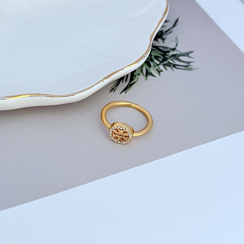 Gold-tone round logo ring with gemstone pavé border, slim band