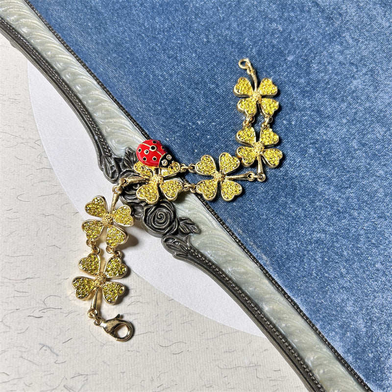 Ladybug and clover charm bracelet with gold-toned chain and yellow-green glitter clovers