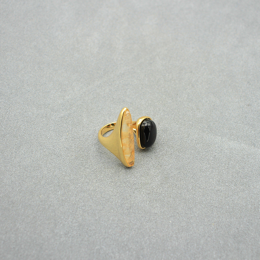 Gold open ring featuring black oval cabochon and arched light marbled setting.