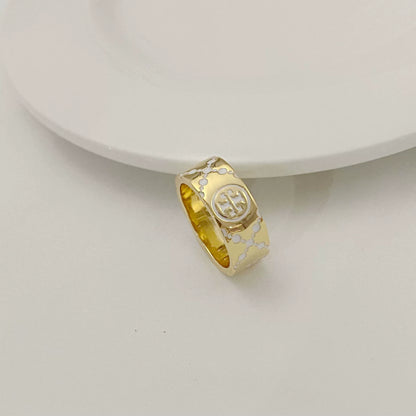 Round metal logo ring with white enamel clover pattern, gold-tone band