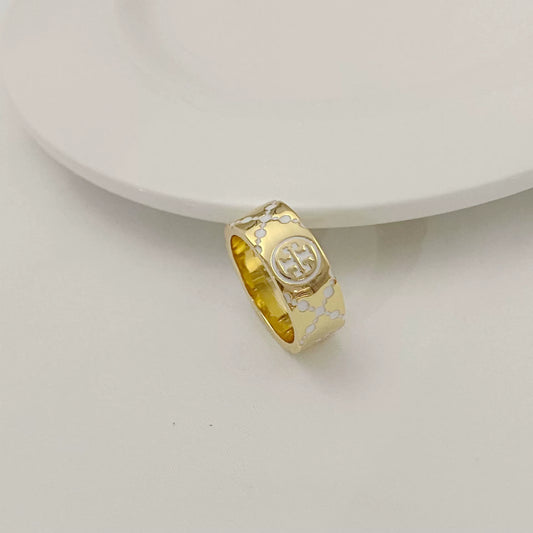 Round metal logo ring with white enamel clover pattern, gold-tone band