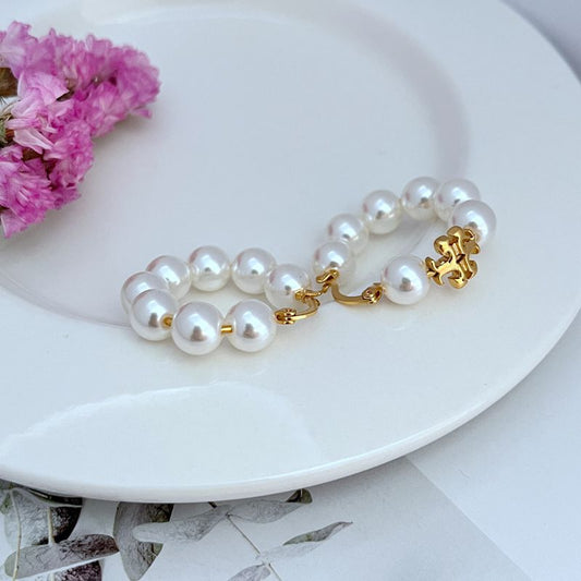 Gold-tone hoop earrings with round white pearl strand and small decorative clasp