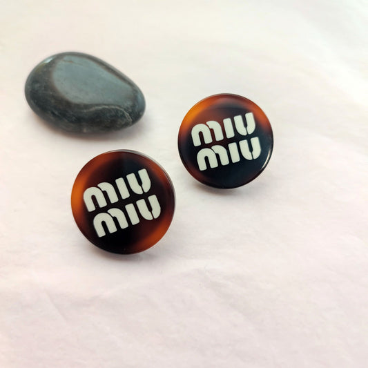 Miu Miu round resin button stud earrings in amber brown with logo