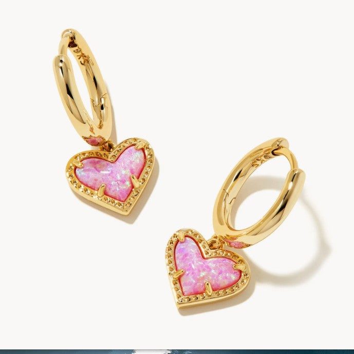 Gold heart pendant hoop earrings with bright pink heart stone and red-toned edge accents