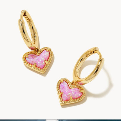 Gold heart pendant hoop earrings with bright pink heart stone and red-toned edge accents