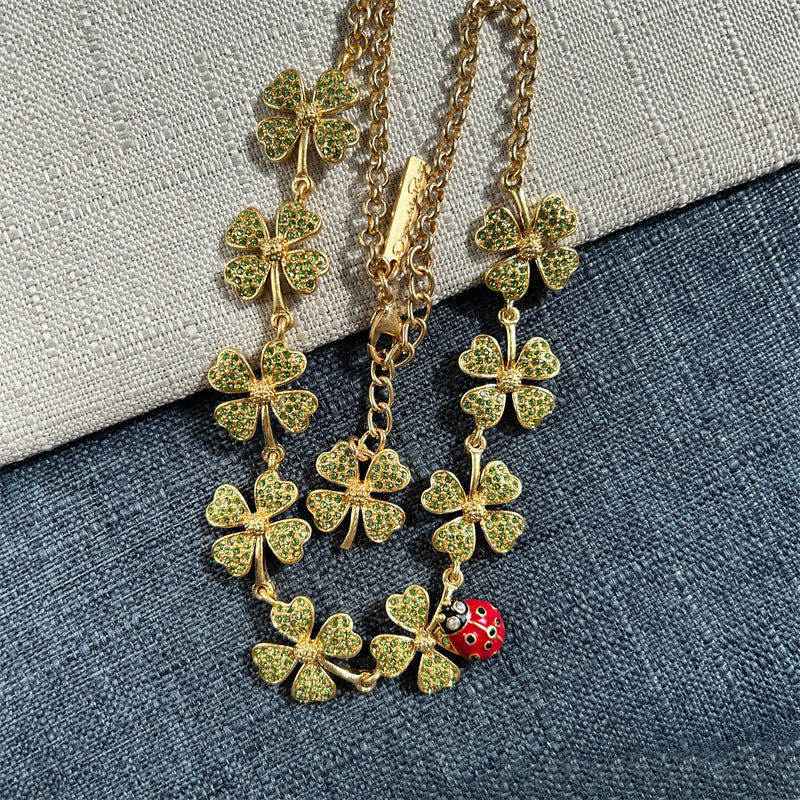 Gold-tone four-leaf clover crystal necklace with dangling ladybug charm and chain