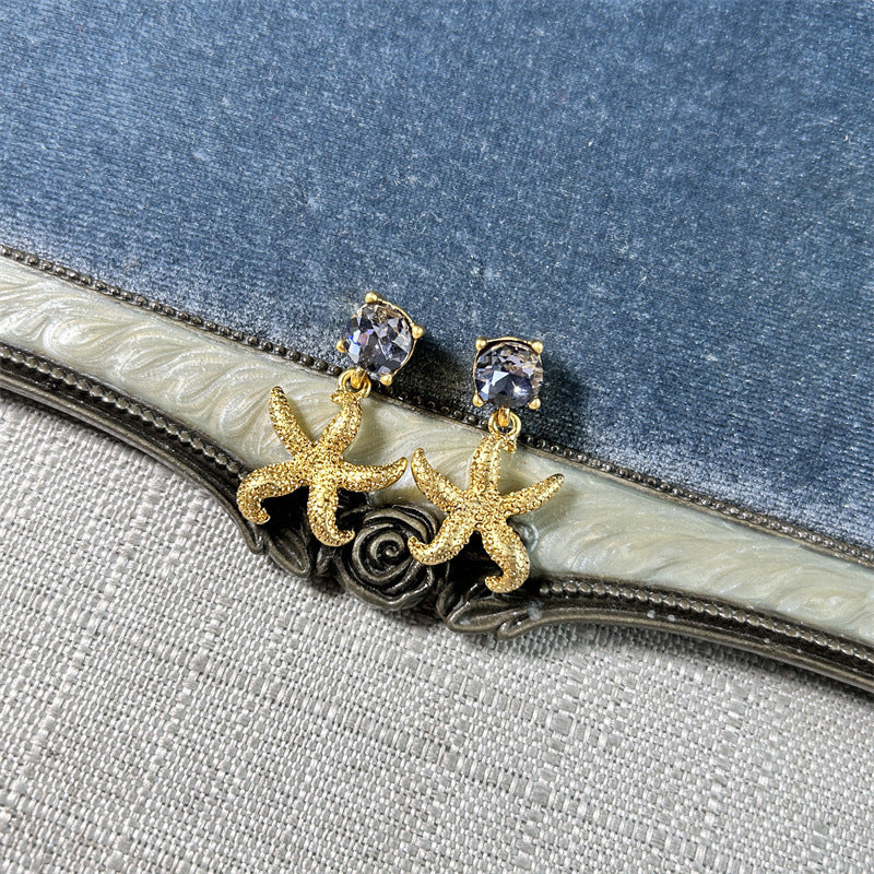 Gold starfish stud earrings with clear round accents