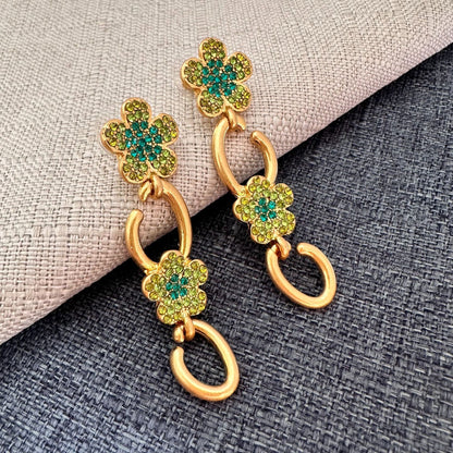 Floral dangle hoop earrings in gold tone with green crystal flower clusters and loops