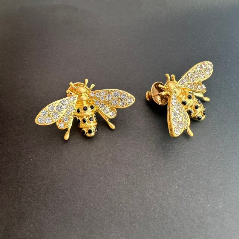 Bee stud earrings with gold-tone setting and clear crystal wings, clasp backing visible