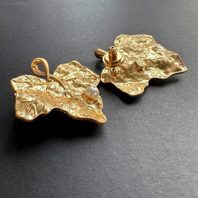 Gold-tone ivy leaf pearl earrings with visible earring post and white pearl center