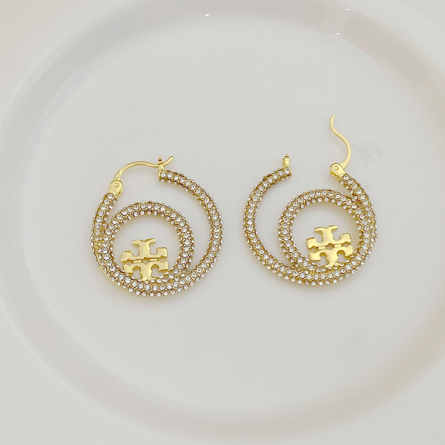 Gold hoop earrings with full diamond pavé and Tory Burch logo charm center