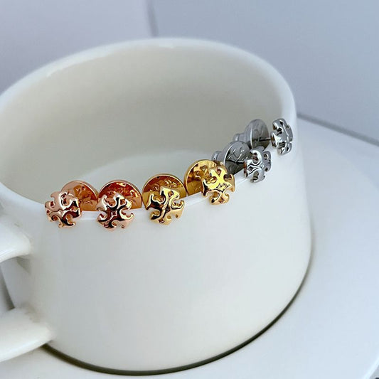 Sweet logo metal stud earrings with interlocking emblem in mixed gold and silver tones