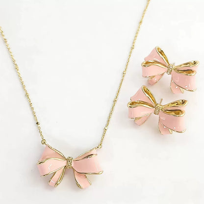 Gold bow pendant necklace with pink enamel ribbon and pearl, with matching stud earrings