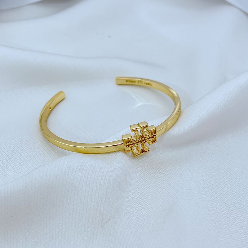 Openwork square logo smooth metal bangle, gold tone close-up with central emblem