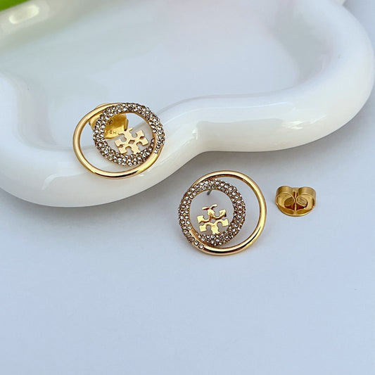 Pair of gold-tone stud earrings, circular frame edged with rhinestones, logo detail
