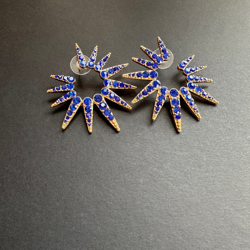 Blue starburst stud earrings with gold-tone settings and small clear stones