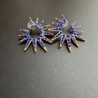 Blue starburst stud earrings with gold-tone settings and small clear stones