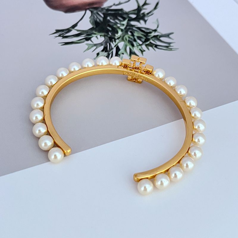 Gold bracelet bangle with pearls around edges and centered logo detail