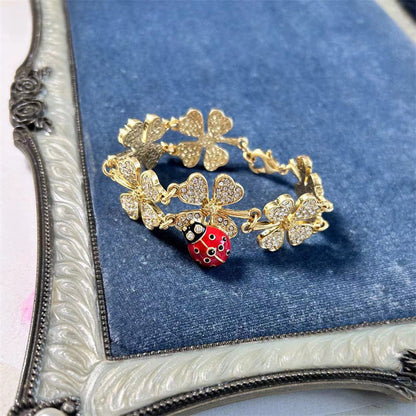 Clover charm bracelet with ladybug centerpiece, gold-tone chain, and glitter clovers