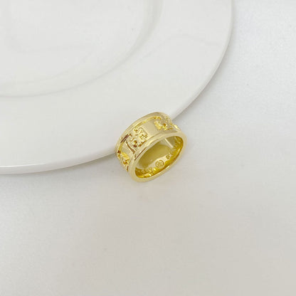 Gold metal letter band ring, close-up view with engraved vertical details