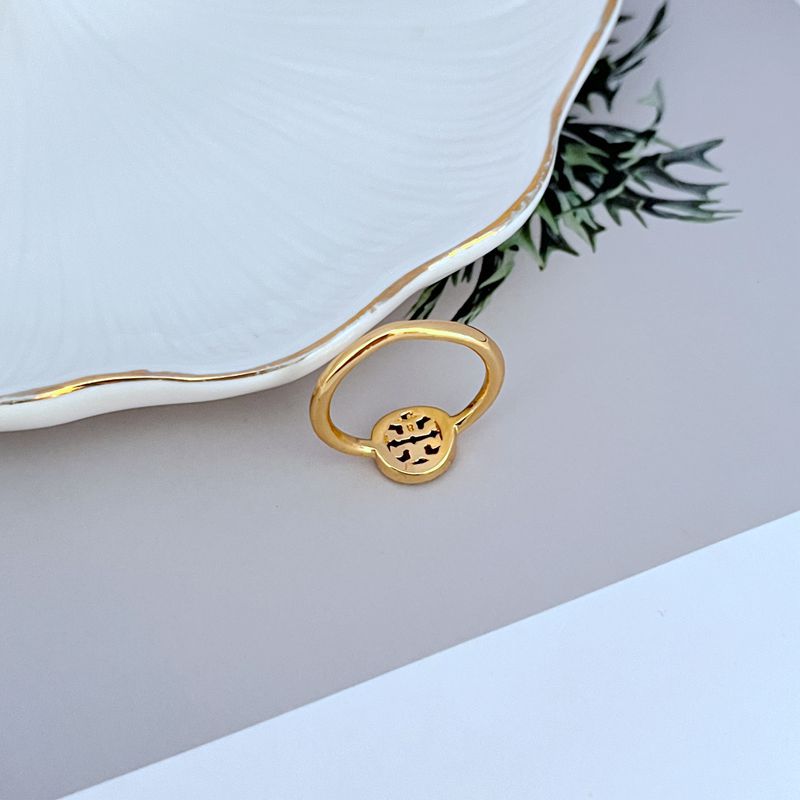Gold-tone openwork logo ring with circular bezel and small pavé stones