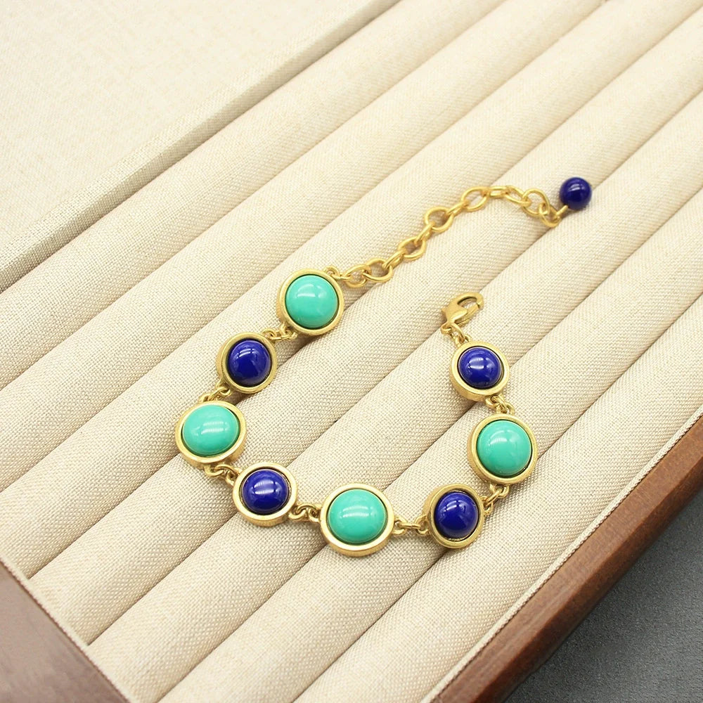 Gold-tone round stone bracelet with turquoise and dark blue beads on display