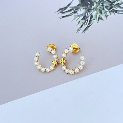 Gold C-shaped hoop earrings with white pearl beads and raised logo detail