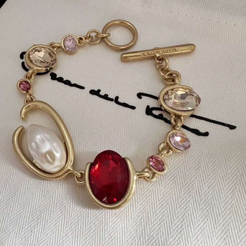 Gold-tone crystal and pearl O-ring bracelet with red oval center stone and pink beads