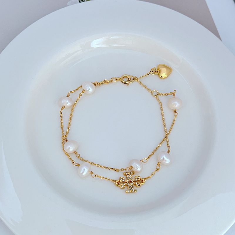 Goldfarbenes doppelreihiges Perlenarmband mit weißen Perlen und Strassblumen-Motiv