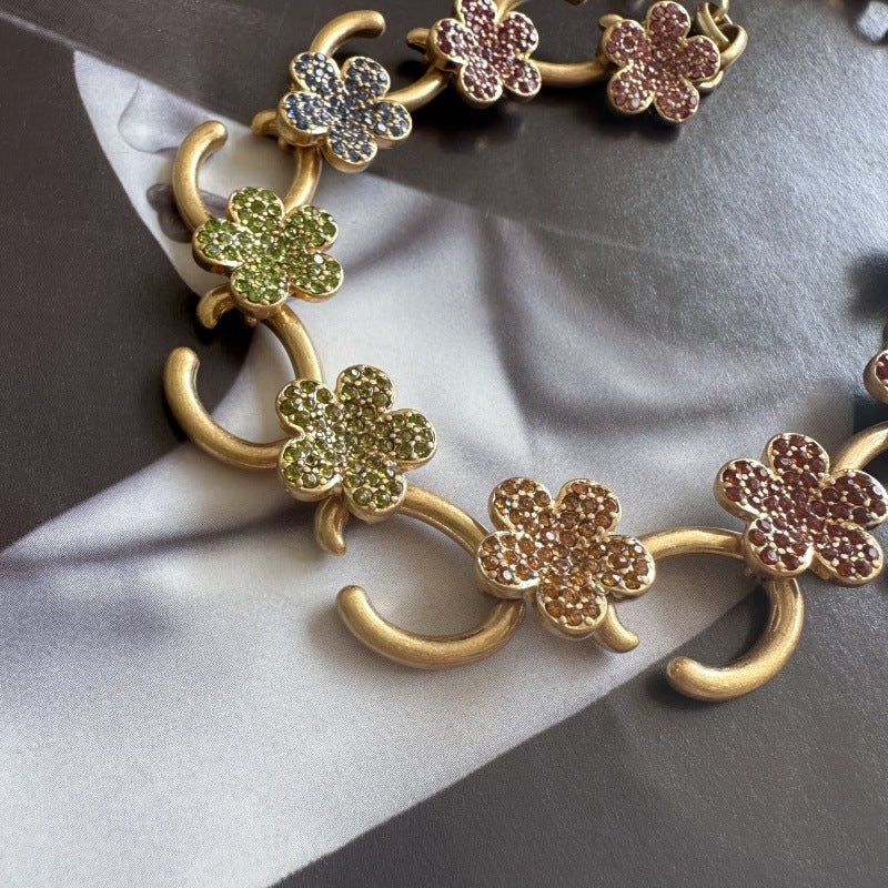 Gold-plated floral pendant necklace with green and maroon rhinestone clover charms