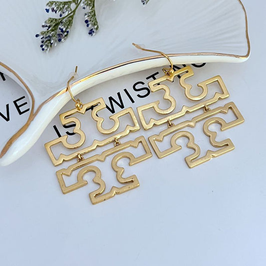 Gold openwork logo drop earrings with long geometric links and fishhook clasps.