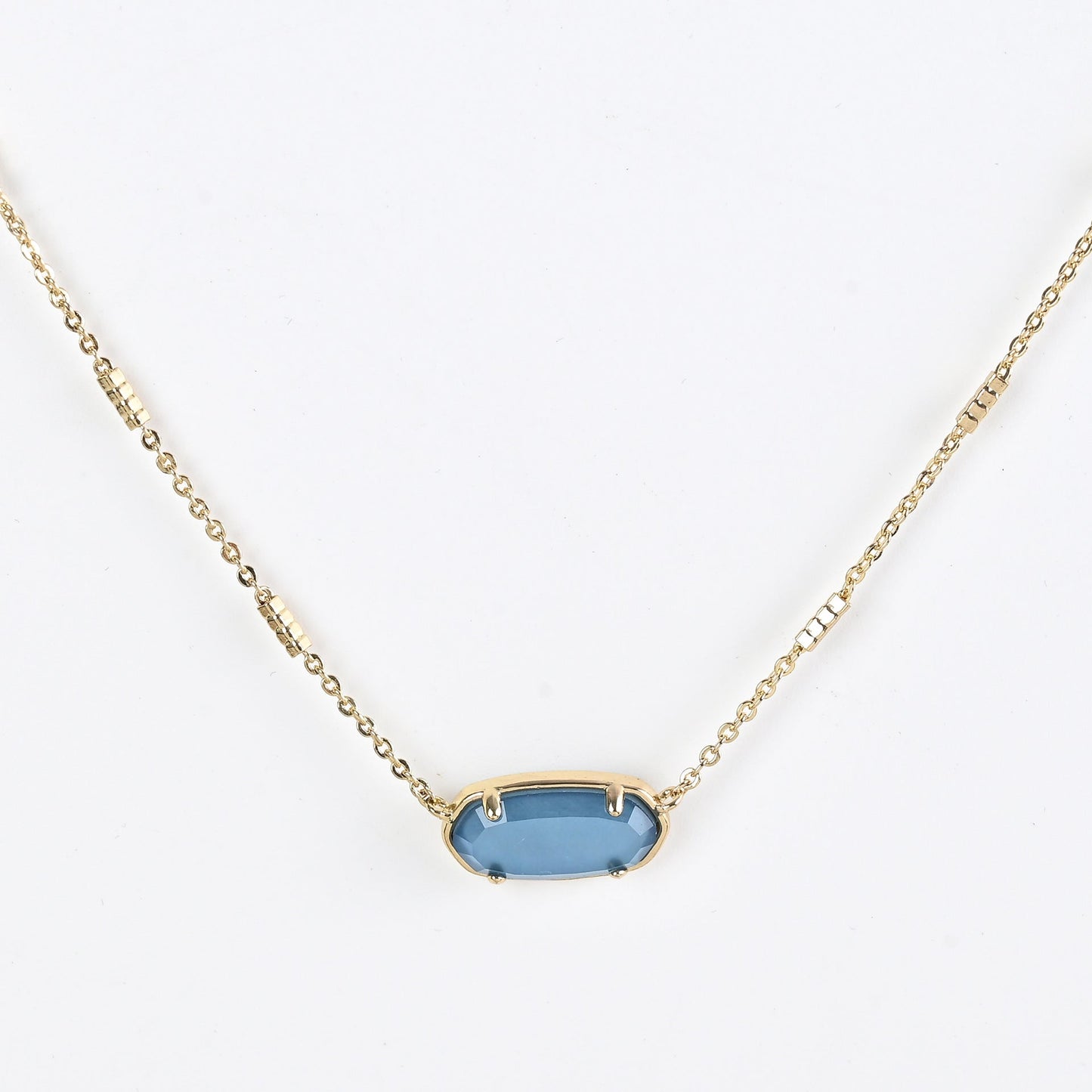 Oval crystal pendant necklace with blue stone and gold bezel on a gold chain