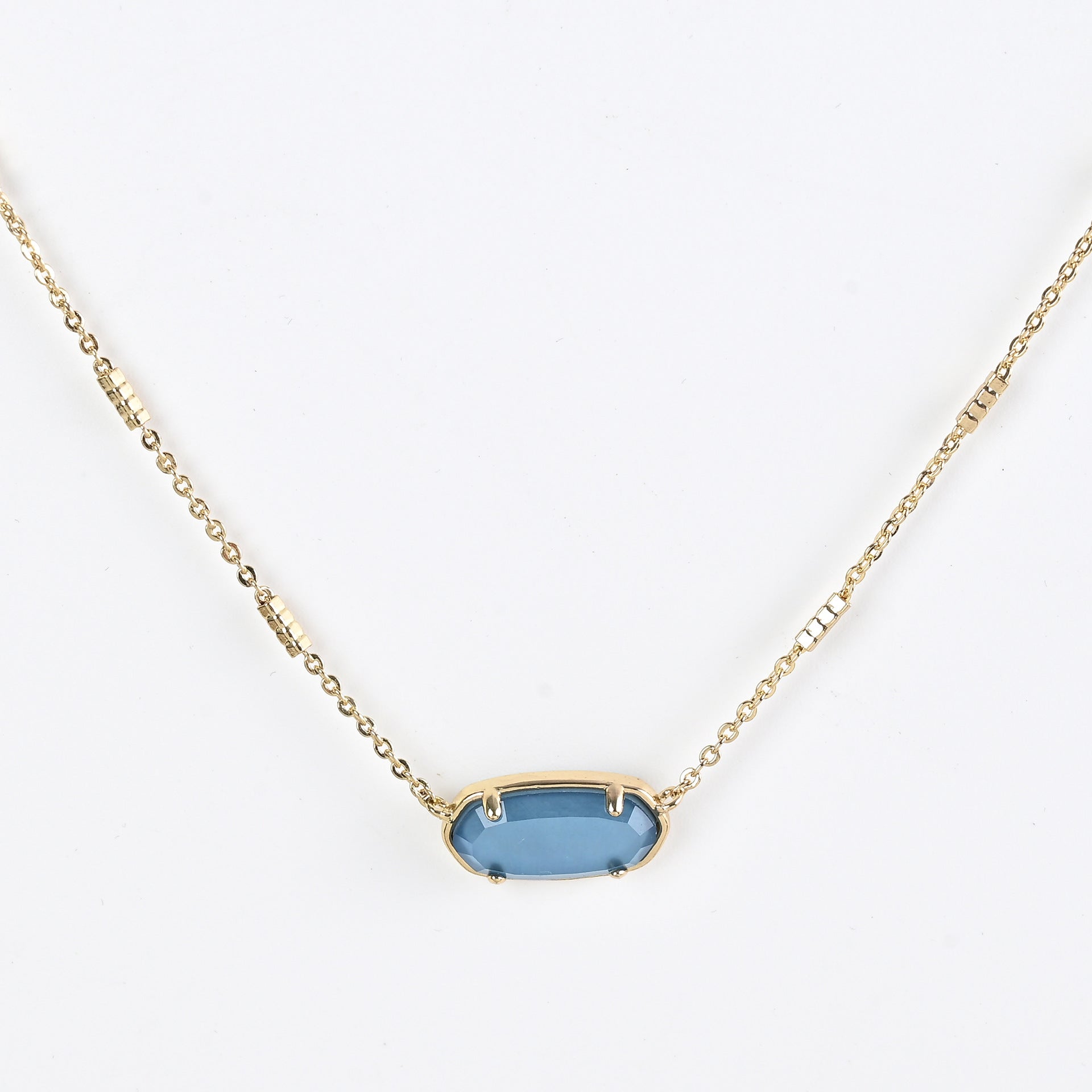Oval crystal pendant necklace with blue stone and gold bezel on a gold chain