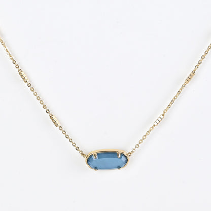 Oval crystal pendant necklace with blue stone and gold bezel on a gold chain