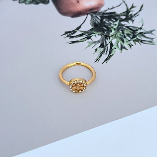 Gold-tone ring with round openwork logo and pavé stones