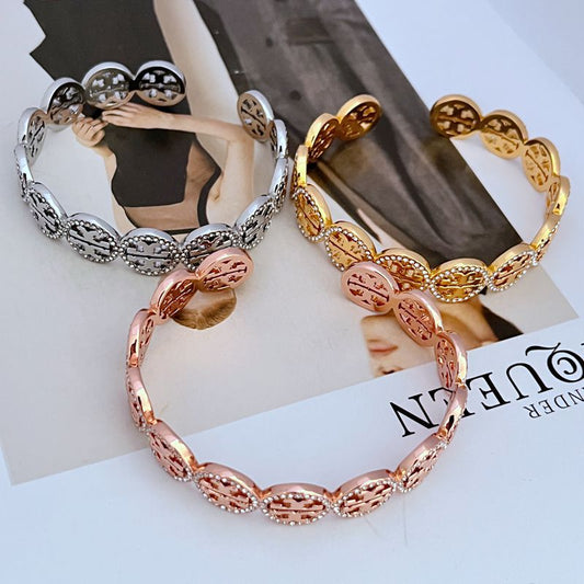 Openwork logo bangle with diamond-studded circular links in gold and rose tones