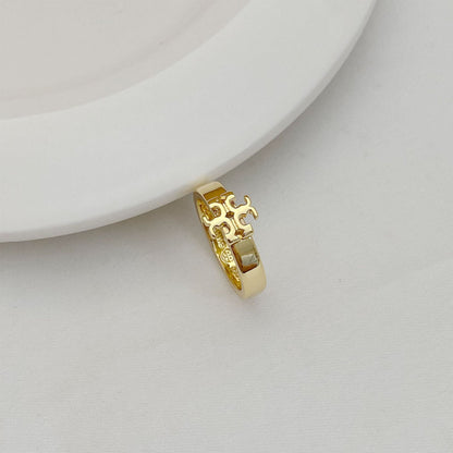 Gold-tone ring with rectangular cutout pattern and raised emblem on top