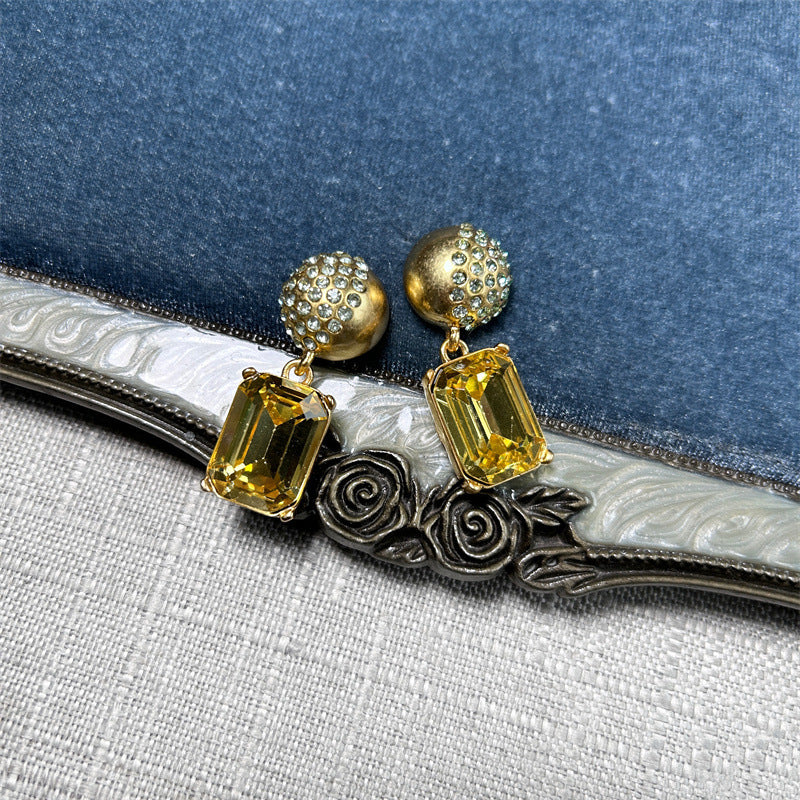 Gold-tone stud earrings with yellow square-cut drop stones and round jeweled caps