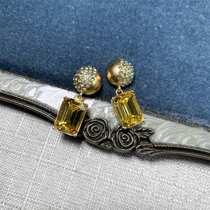 Gold-tone stud earrings with yellow square-cut drop stones and round jeweled caps