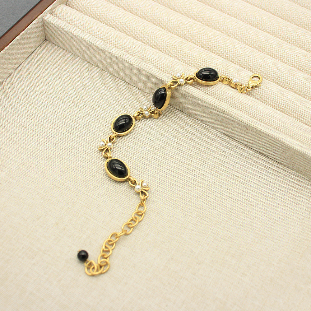 Vintage oval black glass necklace with gold chain and small butterfly charm accents